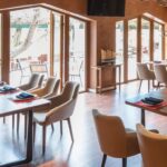 Thumbnail of http://Modern%20restaurant%20interior%20with%20rustic%20design%20featuring%20natural%20wood%20tables%20and%20chairs,%20warm%20golden%20walls,%20large%20windows,%20soft%20lighting%20fixtures,%20comfortable%20booth%20and%20table%20seating,%20earthy%20neutral%20tones,%20and%20cosy%20atmosphere%20in%20Dulwich