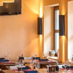 Thumbnail of http://Cosy%20restaurant%20interior%20with%20warm%20neutral%20colour%20palette,%20natural%20wood%20dining%20furniture,%20golden%20amber%20walls,%20soft%20lighting,%20comfortable%20seating%20arrangements,%20large%20windows,%20rustic%20modern%20design,%20and%20inviting%20atmosphere%20in%20Dulwich