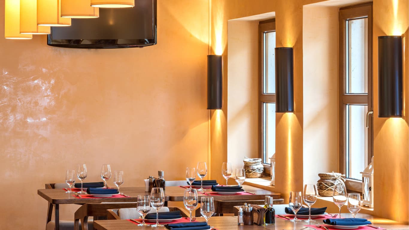 Cosy restaurant interior with warm neutral colour palette, natural wood dining furniture, golden amber walls, soft lighting, comfortable seating arrangements, large windows, rustic modern design, and inviting atmosphere in Dulwich