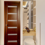 Thumbnail of http://Spacious%20walk-in%20closet%20with%20wooden%20door,%20white%20fitted%20wardrobes,%20illuminated%20shelving%20and%20modern%20minimalist%20design