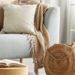 Thumbnail of http://Soft%20boho%20corner%20with%20light%20grey%20sofa,%20neutral%20cushions,%20woven%20basket,%20and%20wooden%20tables.