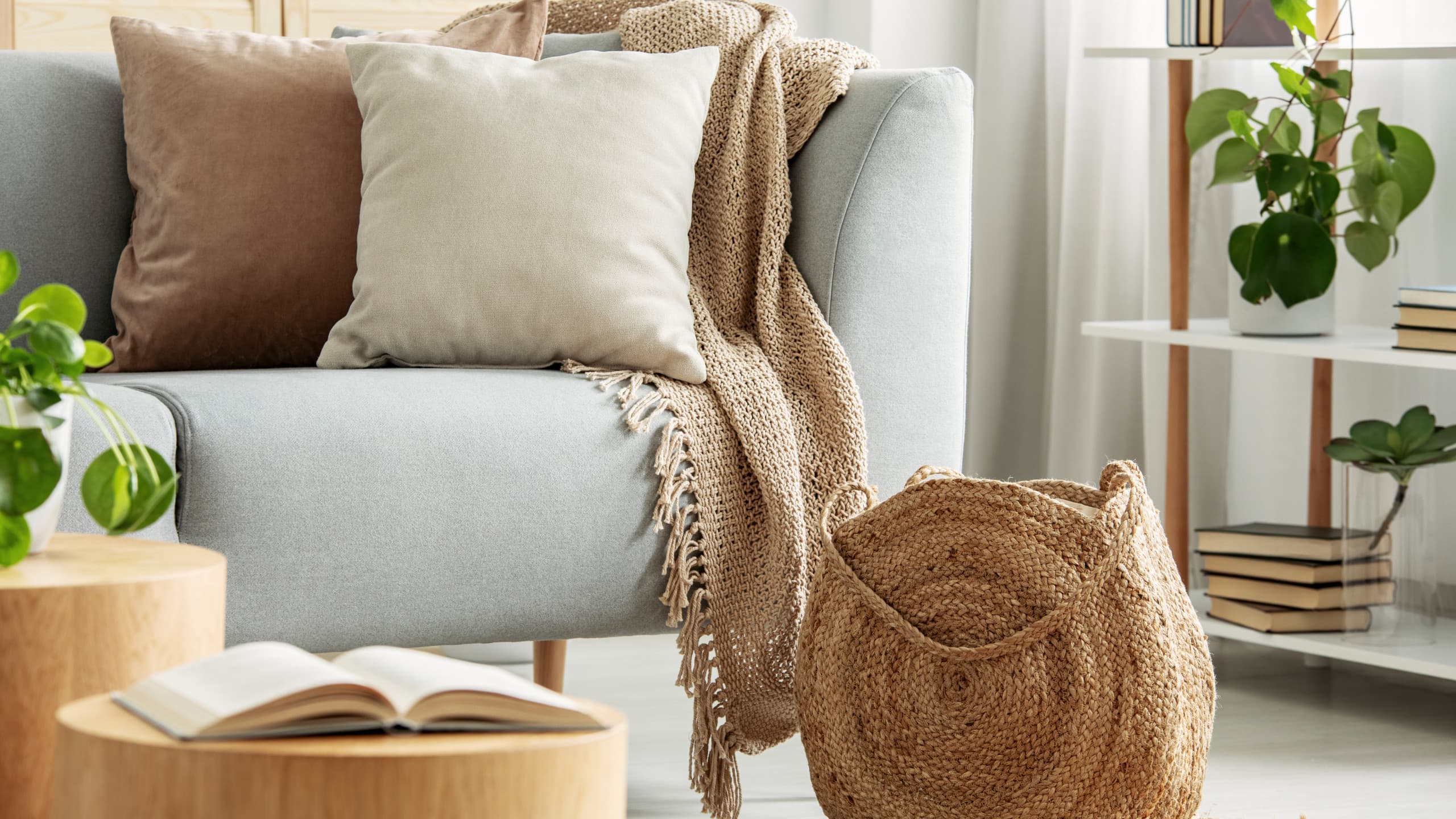 Soft boho corner with light grey sofa, neutral cushions, woven basket, and wooden tables.