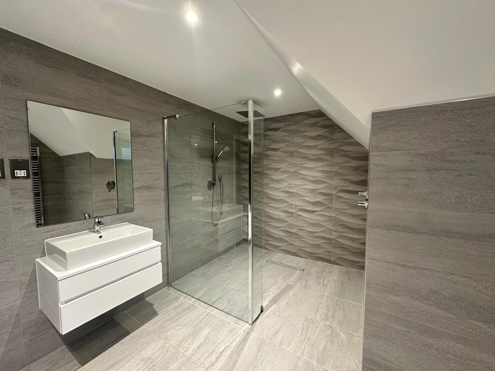 Luxury bathroom lighting design with recessed spotlights highlighting stone-effect tiles in Knightsbridge
