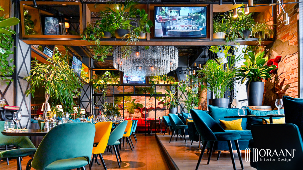 A restaurant layout by Oraanj Interior Design in London, UK includes a stylish space with brilliant seating elements alongside greenery features and a distinctive crystal chandelier.